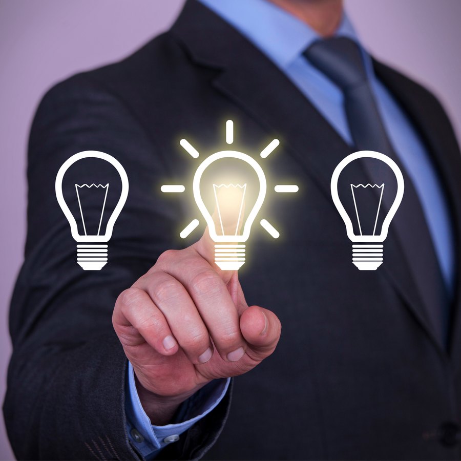 A hand selecting a glowing lightbulb from a row of bulbs