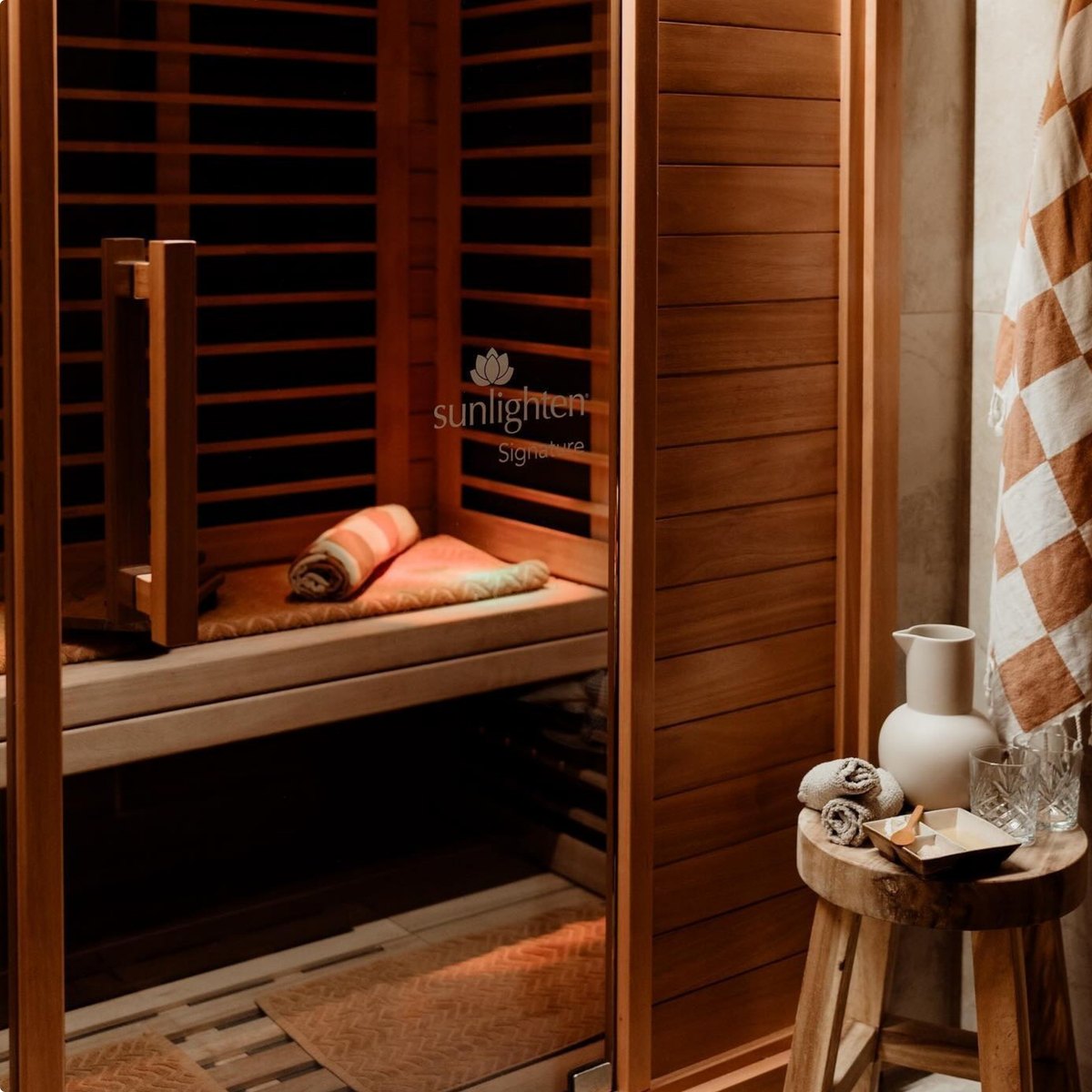 Interior of a Sunlighten Signature infrared sauna with folded towels and a ceramic jug